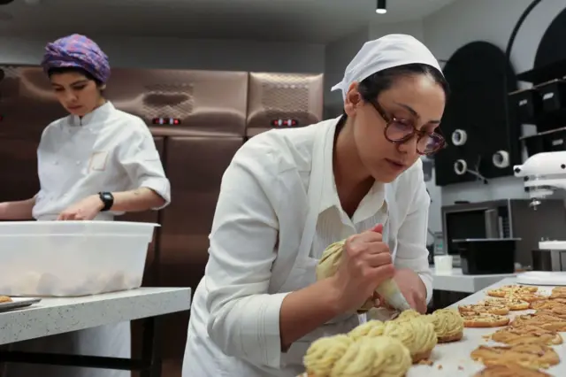 La pastelera iraní Shahrzad Shokouhivand (derecha) trabaja en la cocina de su empresa de pastelería de lujo en Teherán